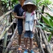 Sur un pont en bambous avec le chapeau traditionne